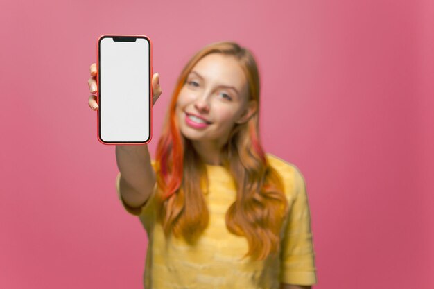 Feche o smartphone na mão de uma garota sorridente simulando aplicativos e serviços móveis de telefone de tela em branco