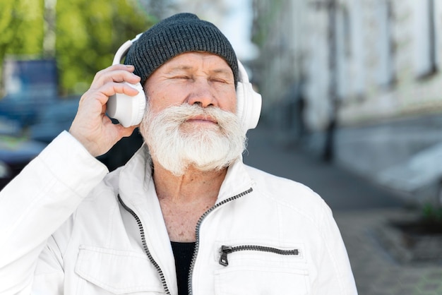 Feche o velho usando fones de ouvido