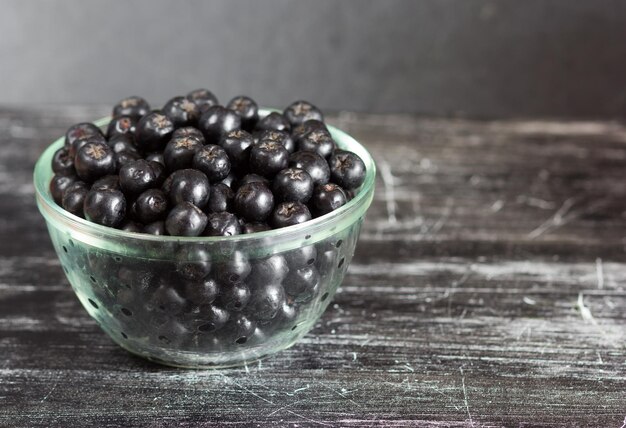 Feche os chokeberries na tigela de vidro no fundo preto