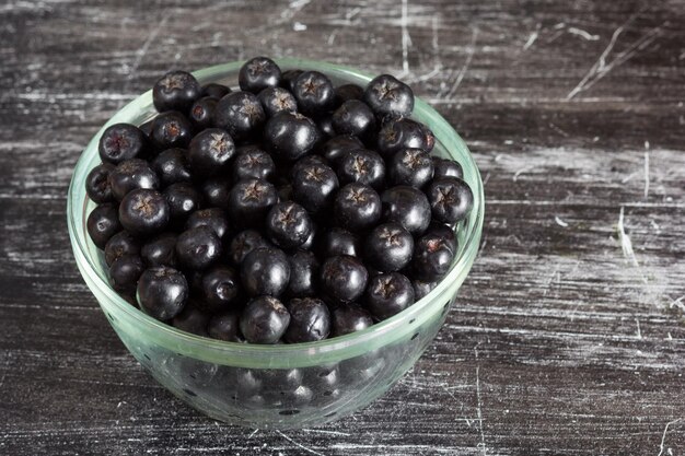 Feche os chokeberries na tigela de vidro no fundo preto