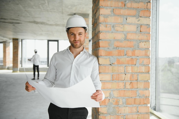 Feche os engenheiros que trabalham em um canteiro de obras segurando um projeto de engenharia e conceito de arquitetura