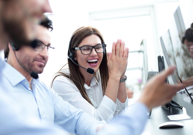 Feche os funcionários felizes do call center sentados em sua mesa