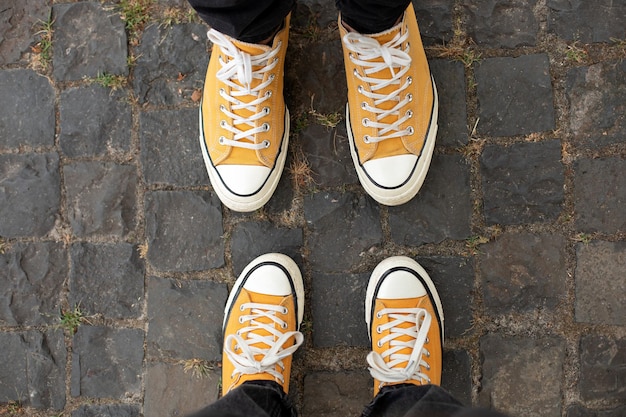 Feche os pés de homem e mulher em elegantes sapatos casuais em tênis amarelos