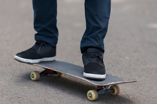 Feche os pés do jovem no skate