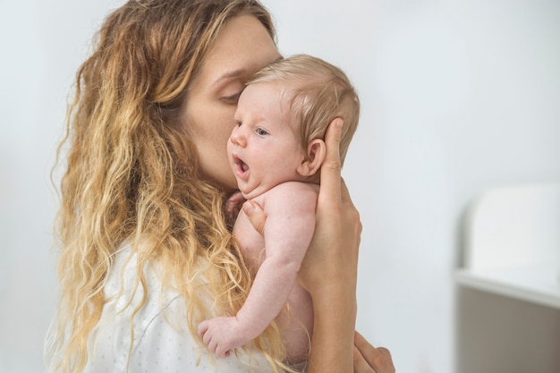 Foto feche os rostos da jovem mãe feliz e fofo bebê recém-nascido.