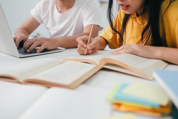 Feche um estudante asiático lendo livros e estudando tutoria juntos