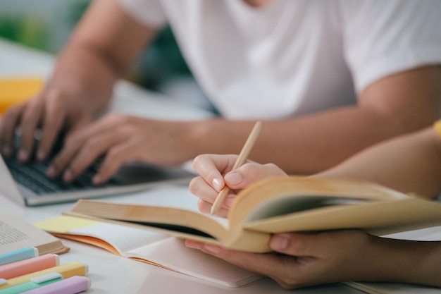 Feche um estudante asiático lendo livros e estudando tutoria juntos