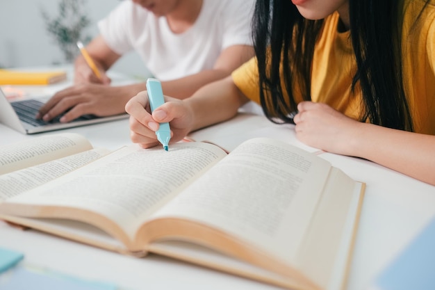 Feche um estudante asiático lendo livros e estudando tutoria juntos