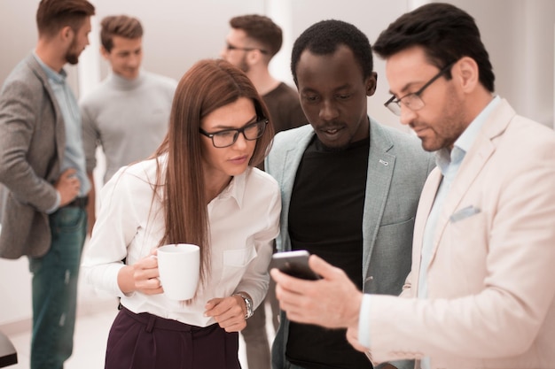 Feche um grupo de funcionários lendo uma mensagem em um smartphone