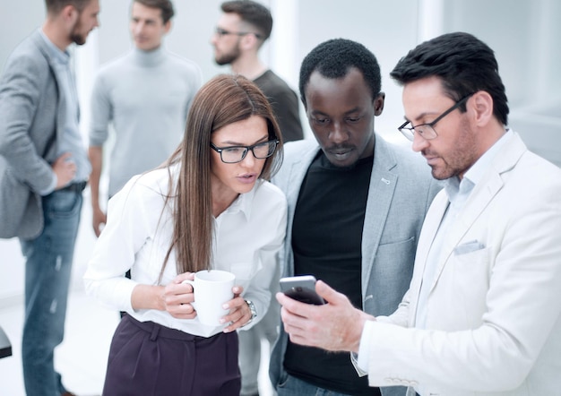 Feche um grupo de funcionários lendo uma mensagem em um smartphonepessoas e tecnologia