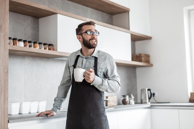 Feche um jovem de avental na cozinha de casa