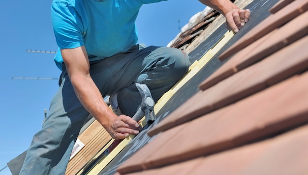 Feche um trabalhador segurando um martelo e reformando o telhado de uma casa