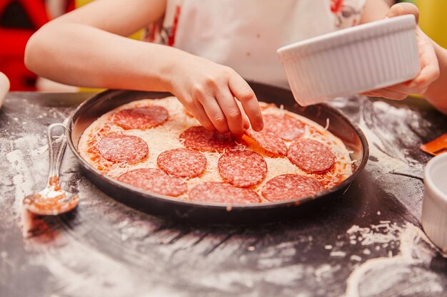 Feche uma garotinha preparando uma pizza para uma master class