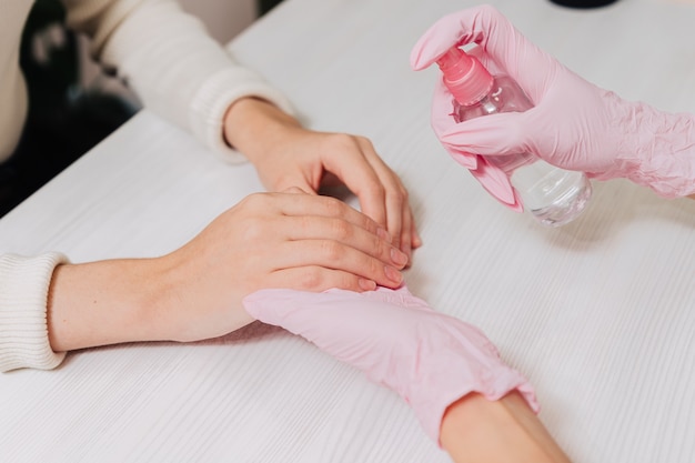 Fechem as mãos femininas. Mãos em luvas de borracha rosa tratam a pele das mãos com um anti-séptico.