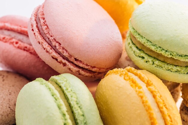 Fecho de macarons multicoloridos, pastelaria gananciosa de macaroon francês sobre fundo branco macarons sobremesa f