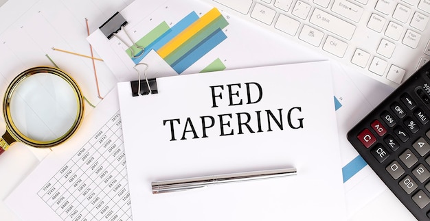 FED TAPERING texto sobre papel blanco sobre el fondo claro con papel de gráficos