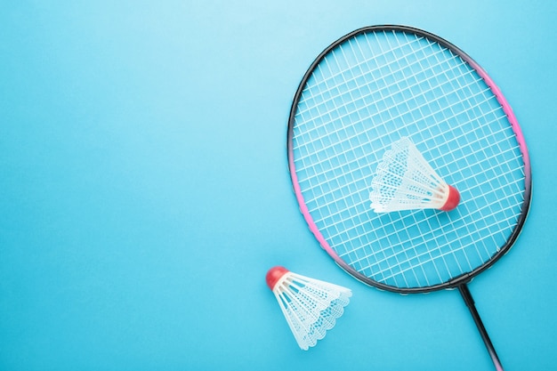 Federbälle und Badmintonschläger auf blau.