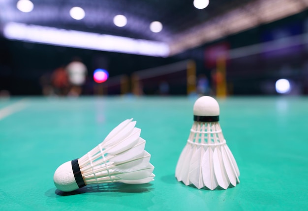 Federball auf grünem Badmintonplatz mit Spieler im Hintergrund