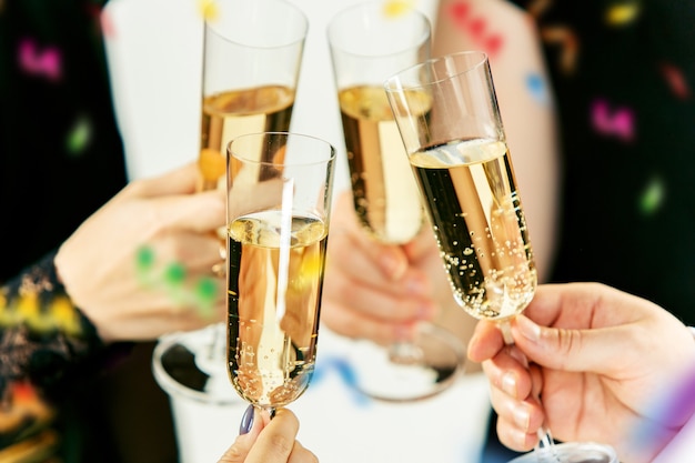 Feier. Hände, die die Gläser Champagner und Wein halten, die einen Toast machen. Das Party-, Alkohol-, Lifestyle-, Freundschafts-, Feiertags-, Weihnachts-, Neu-, Jahres- und Klirrkonzept