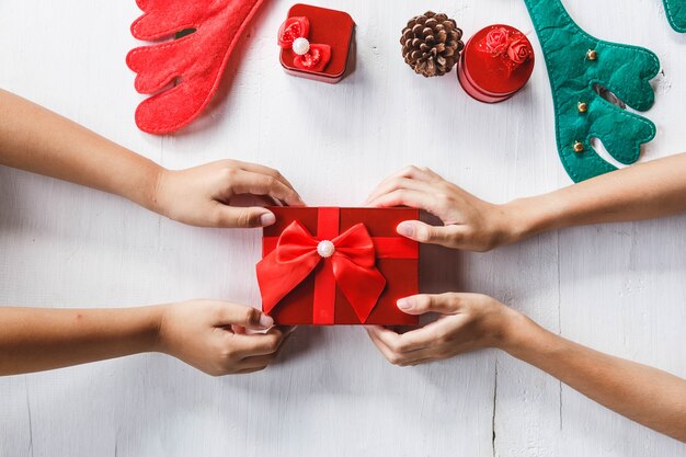 Feier-Party- und Weihnachtstag-Konzeptideen mit der Hand der jungen Person, die Geschenkboxdekoration mit buntem Konfetti, Papierkunst auf weißem Farbhintergrund gibt