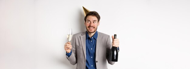 Feier- und Feiertagskonzept alles Gute zum Geburtstag Typ in Anzug und Partyhut, der Champagner hält