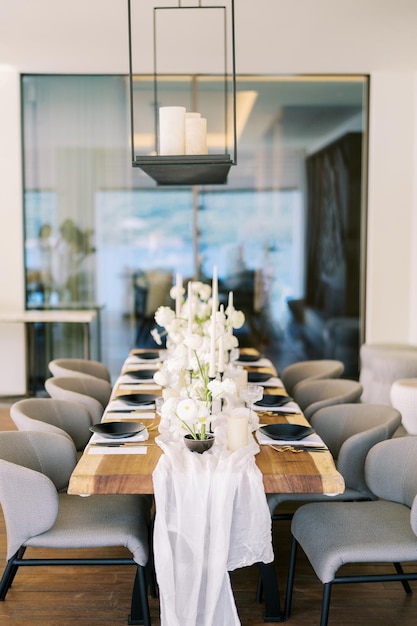 Foto feierlicher tisch mit weißen blumen und schwarzem geschirr in einem restaurant mit kerzen auf einem hängenden regal