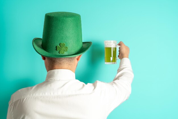 Feiern des St. Patrick's Day Hinterer Mann mit grünem Hut hebt sein grünes Bier an, um zu feiern