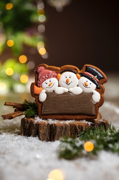 Feiertag traditionelles Essen Bäckerei. Lebkuchen drei lustige Schneemänner in gemütlicher warmer Dekoration mit Girlandenlichtern