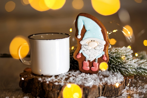 Feiertag traditionelles Essen Bäckerei. Lebkuchen-Märchen-Zwerg in gemütlicher Deko mit Girlanden-Lichtern und einer Tasse heißen Kaffees