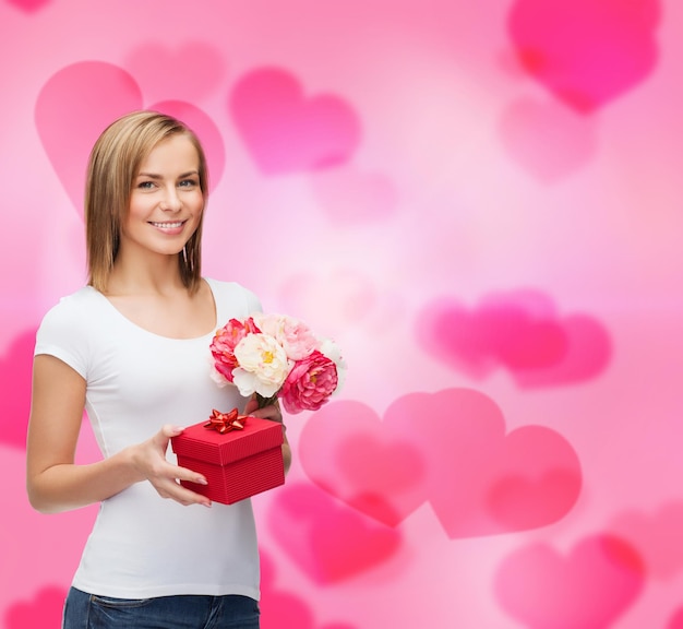 Feiertage, Liebe und Blumenkonzept - junge Frau mit Blumenstrauß und roter Geschenkbox