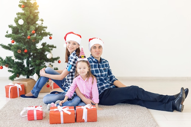 Feiertage und festliches Konzept - glückliches Familienporträt durch Weihnachtsbaum.