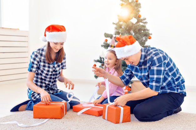 Feiertage und Geschenkkonzept - Porträt einer glücklichen Familie, die zur Weihnachtszeit Geschenke öffnet.