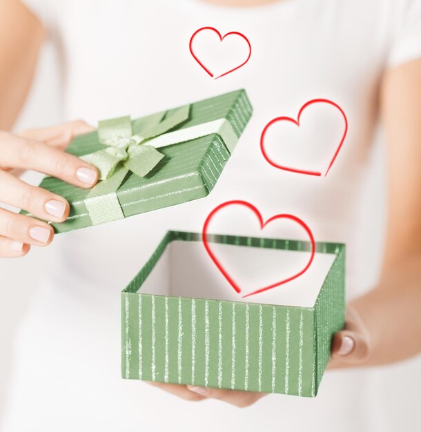 Feiertage und Liebeskonzept - Nahaufnahme von Frauenhänden, die Geschenkbox öffnen