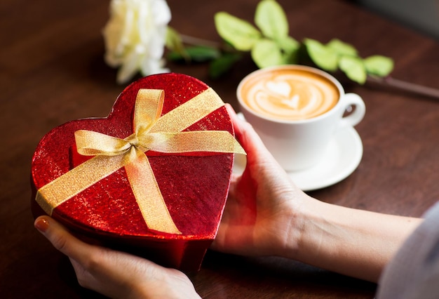 Feiertage, Valentinstag, Liebes- und Menschenkonzept - Nahaufnahme von Händen, die eine herzförmige Geschenkbox halten