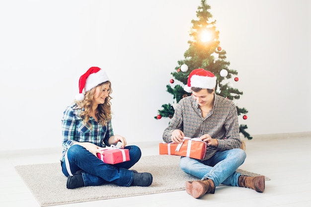 Feiertage, Weihnachten und Familienkonzept - Junges glückliches Paar, das zu Hause Geschenke öffnet.