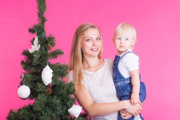 Feiertags-, Familien- und Weihnachtskonzept - junge Mutter mit ihrer kleinen Tochter nahe Weihnachtsbaum auf