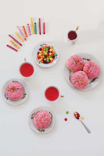 Feiertags-Geburtstagsfeier-Komposition mit bunten rosa glasierten Donuts auf weißer Tisch-Flatlay-Draufsicht