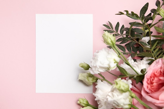 Feiertagsgrußkartenmodell mit Blumen auf hellrosa Hintergrund Draufsicht flach lag