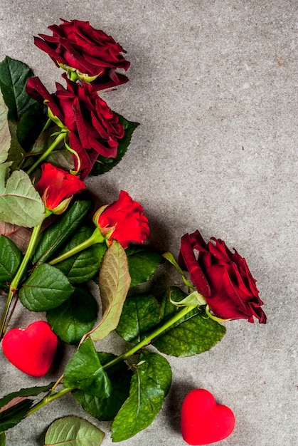 Feiertagshintergrund, Valentinstag. Strauß roter Rosen, Krawatte mit einem roten Band, mit eingewickelter Geschenkbox. Kopieren Sie auf einem grauen Steintisch die Draufsicht des Raums