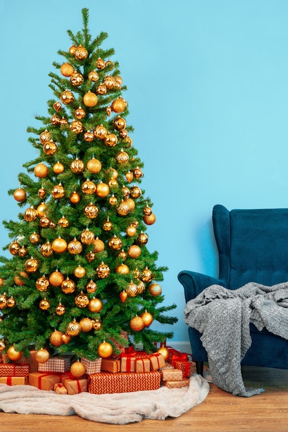 Feiertagsinnenraum, schöner verzierter weihnachtsbaum mit blauem lehnsessel