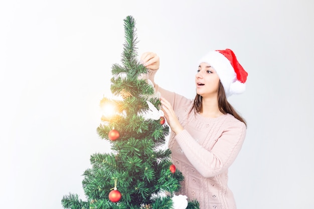 Feiertagskonzept - Mädchen im Sankt-Hut verzierten Weihnachtsbaum. Warten auf Weihnachten.