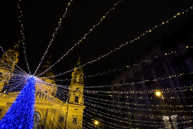 Feiertagspelzbaum mit Lichtern am Weihnachtsmarkt vor Heiligem Istvan Basilika, Budapest, glättend, Dezember 2015