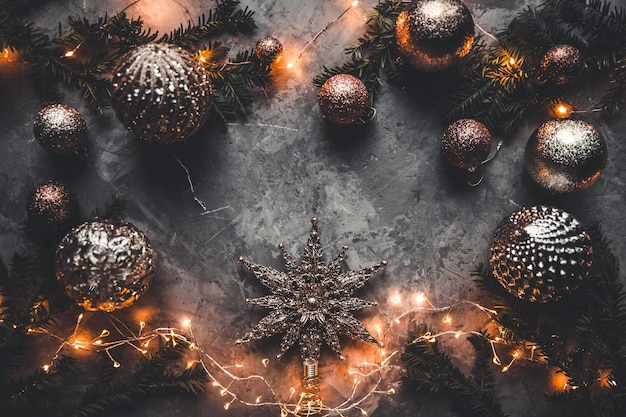 Feiertagsrahmen von Weihnachtsdekorationen auf blauem dunklem Stuckbetonhintergrund mit Tannenzweig, goldenen Kugeln, Sternen, Weihnachtssocken und Spielwaren. Elegantes Silvester. Ansicht von oben.