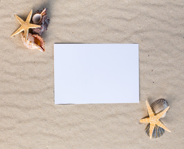 Feiertagsstrandkonzept mit Oberteilen, Seesternen und einer leeren Postkarte