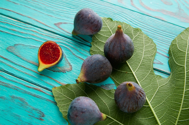 Feigen rohe geschnittene früchte und feigenbaumblätter auf blau