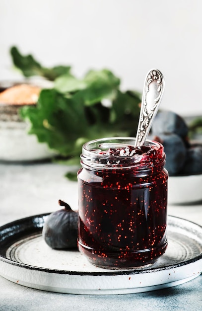 Feigenmarmelade im Glas mit frischen blauen Feigen Hausgemachte Zubereitungen und Konserven Grauer Hintergrundkopierraum