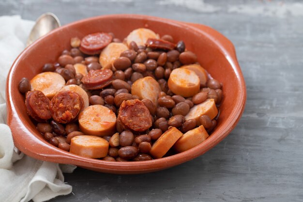 Foto feijão com linguiça defumada e linguiça em prato de cerâmica