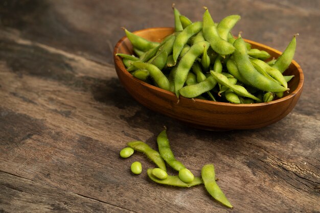 feijão edamame em uma tigela de madeira na mesa de madeira texturizada