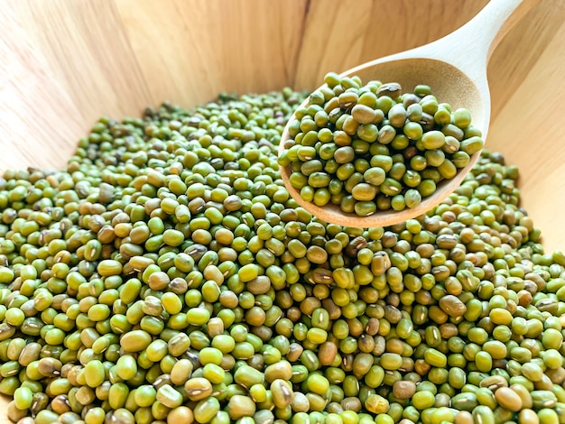 Feijão verde em uma colher de pau em uma tigela de madeira