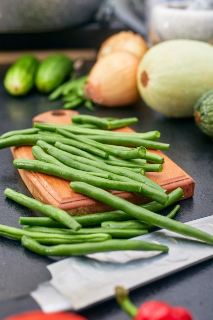 Feijão verde picado em uma placa de madeira com vegetais